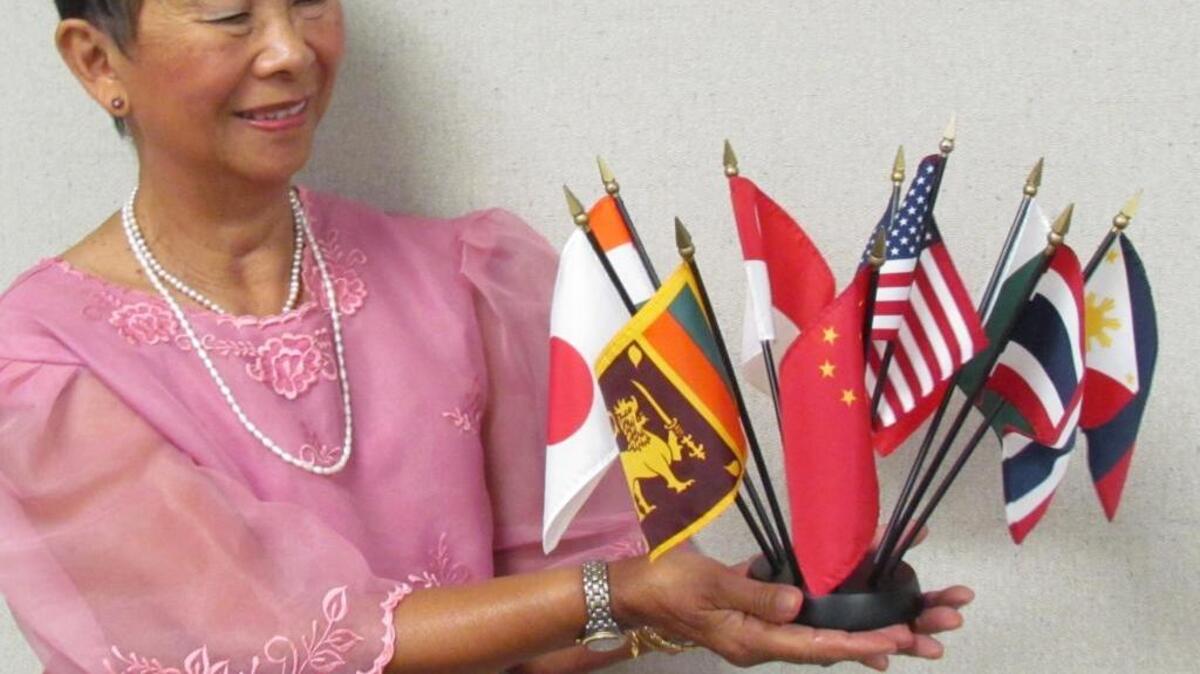 
Mari-Lou Wong-Chong, chair of the 12th annual Brunswick County Intercultural, holds flags from some of the countries represented in the festival and wears a blouse from her native Philippines called a barong tagalog. “It’s loose because it’s hot in the Philippines,” she said. 
