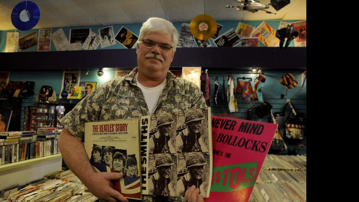 
Gary Finkenbiner stands last year with “The Beatles Story,” “The Smiths” and a Sex Pistols album in the vinyl record section of his store, Kilgor Trouts Music & More in downtown Myrtle Beach.
