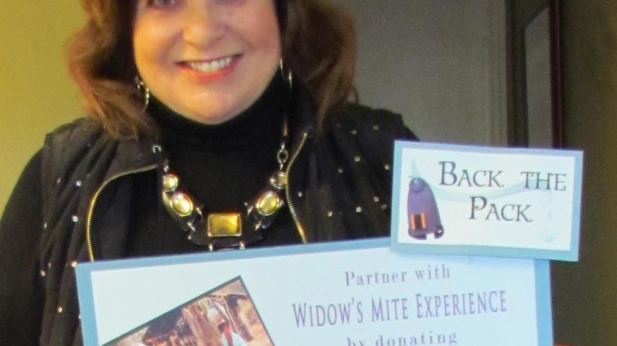 Janet Baker, founder and president of the nonprofit organization Widow’s Mite Experience, displays the poster for the “Back the Pack” project. The $30 donation buys a backpack so women can fill it with water from wells representatives from Widow’s Mite Experience digs and carry it on their backs instead of carrying jars on their heads.