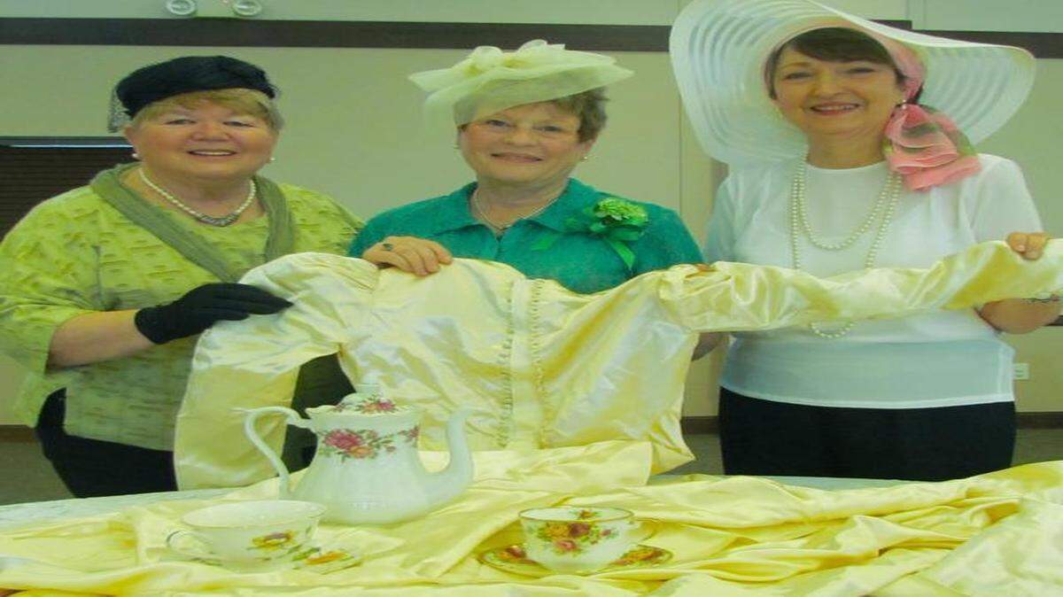 
To prepare for the Vintage Fashion Show, Lorraine Manning (from left) wears a pillbox hat from the 1960s, GeorgAnn Feldman wears a fascinator from the early 20
th
 century, and Pauline DiMartino wears a hat reminiscent of “Downton Abbey.” A vintage teapot, teacup and saucer rest on a bridal gown from 1939. 
