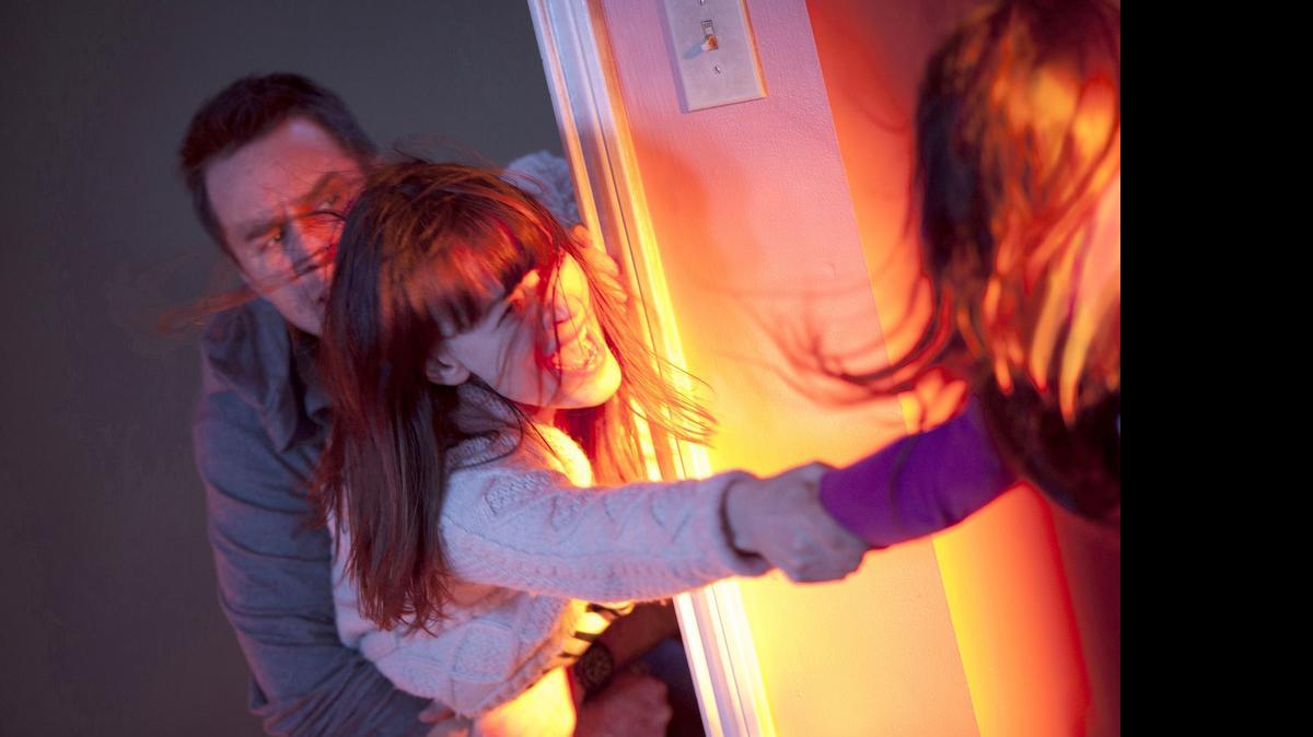 
Eric (Sam Rockwell) and Amy (Rosemarie DeWitt) desperately try to hold on to their daughter, Madison (Kennedi Clements), in “Poltergeist.” 
