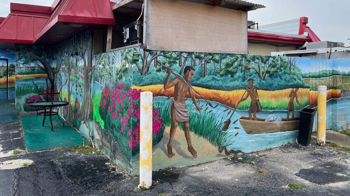 Mural of Yammassee native American tribe fishing the shoreline of Wither’s Swash painted on the side of Cackalacky Fish Company by local artist April Bensch. Cackalacky closed in mid-September 2024.