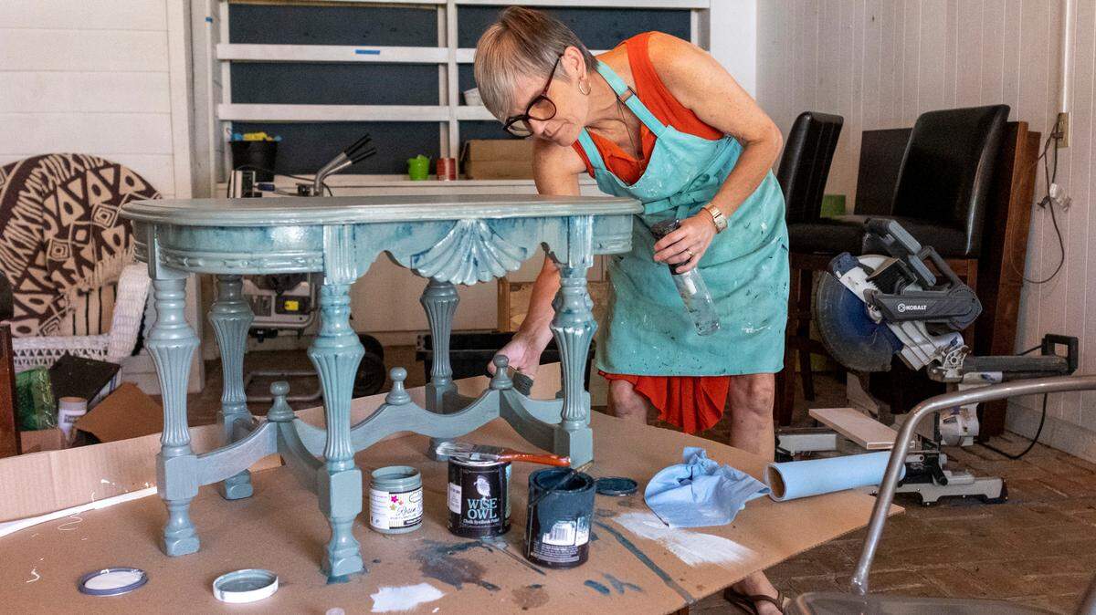 Burke Daniel paints an antique table at Murrells Inlet’s Fringe Vintage Shop in this July 2021 file photo. Randy and Burke Daniel curated works from nine featured South Carolina artists and set aside a section of the shop as an art gallery before it closed in fall 2021.