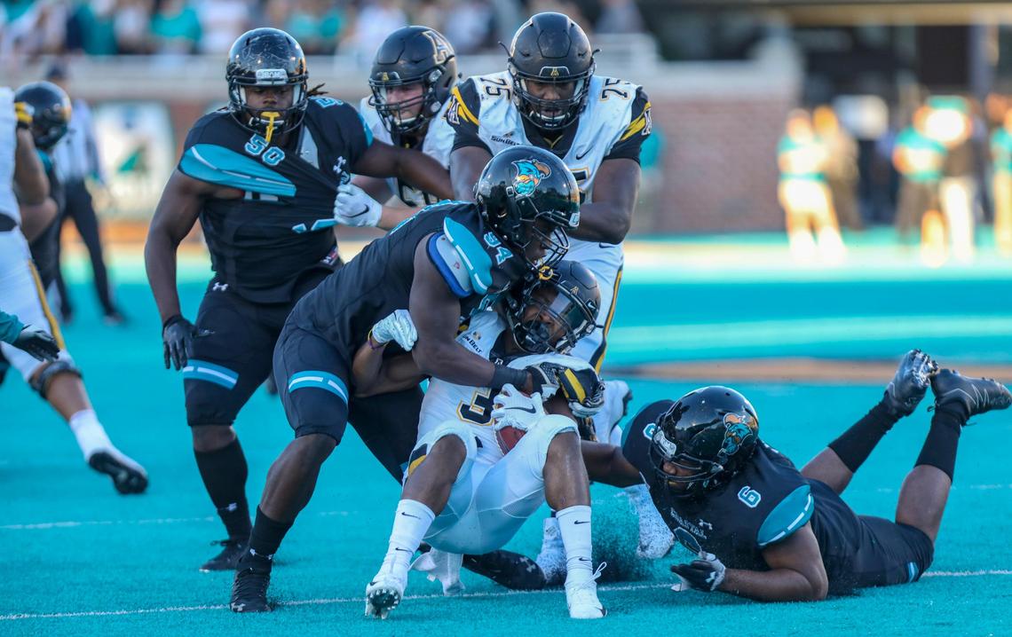 Coastal Carolina sophomore defensive end Jeffrey Gunter (94) and junior defensive tackle Sterling Johnson tackle Appalachian State running back Darrynton Evans in 2018 at Brooks Stadium in Conway.