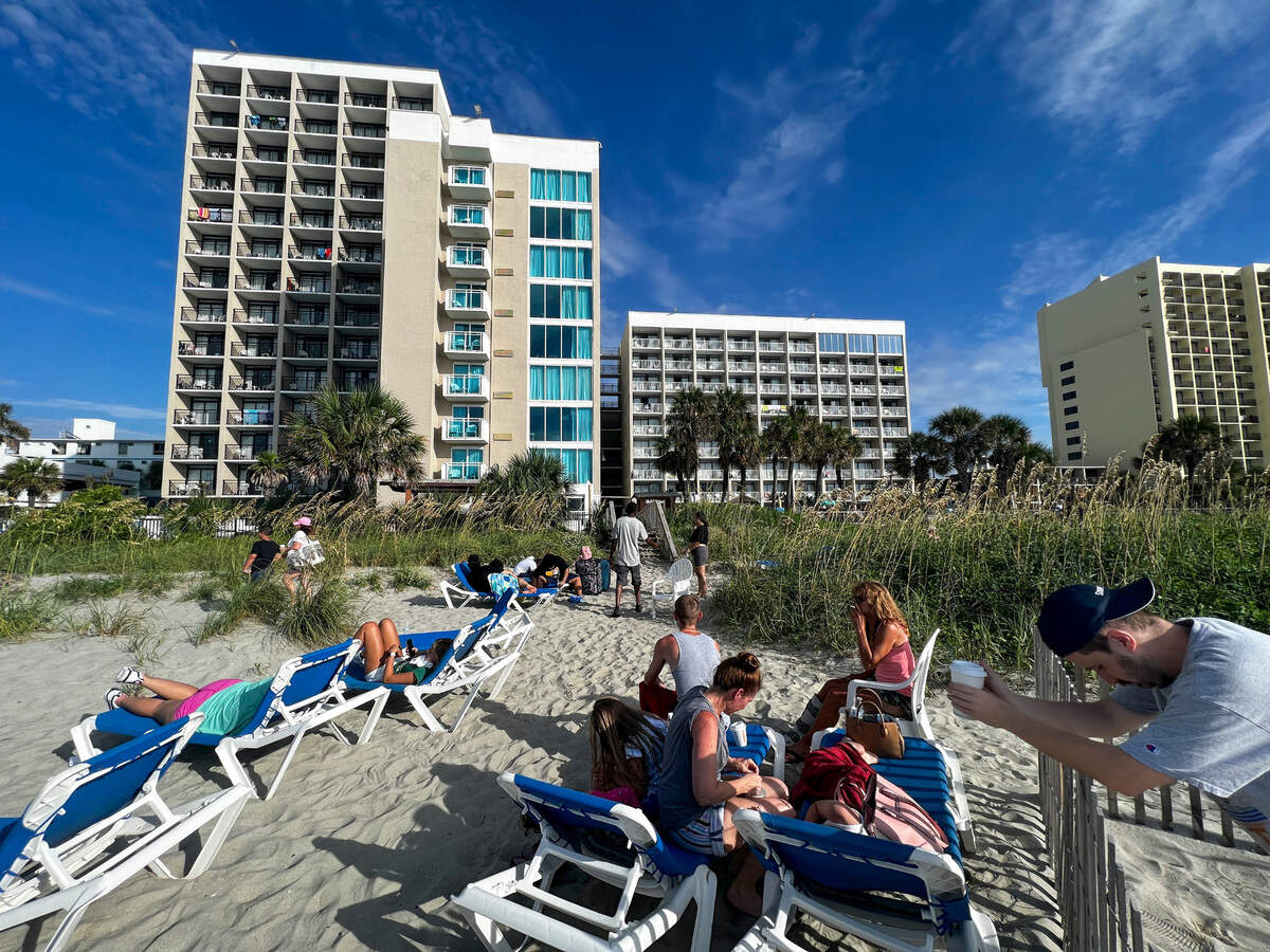 Displaced visitors gather on beach chairs to watch as firefighters respond to the Captain’s Quarters Resort in Myrtle Beach after a fire broke out on Monday morning. Many visitors said they left their rooms without their medications and belongings after hearing about or smelling smoke in the early morning. There were no injuries reported among guests but at least three firefighters were treated for dehydration. Aug. 16, 2023.