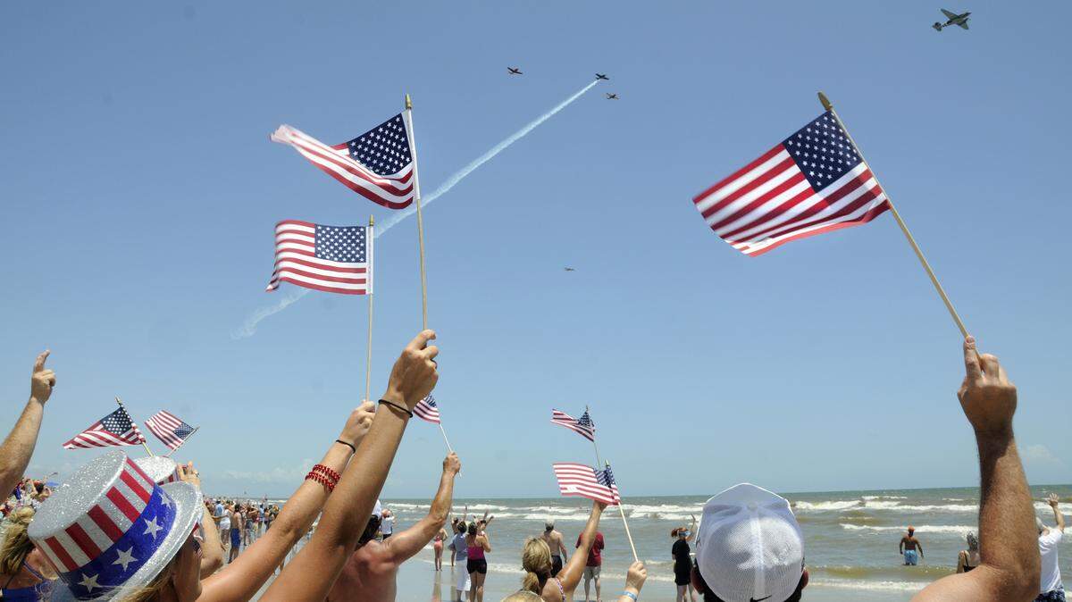 Beachgoers wave American flags during a previous year’s Salute from the Shore.