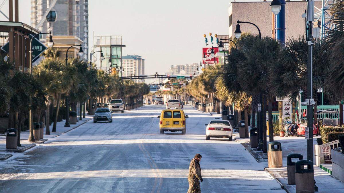 A pedestrian carefully crosses Ocean Boulevard in Myrtle Beach after Winter Storm Grayson in 2018.