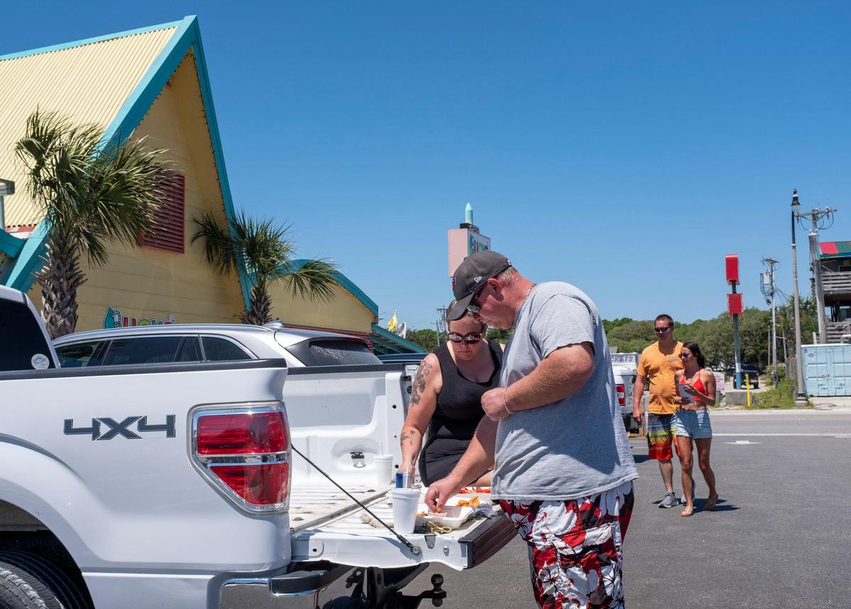 Don and Dana Booker eat their meals on the tailgate of their truck after ordering at Buoys on the Boulevard in North Myrtle Beach. April 28, 2020