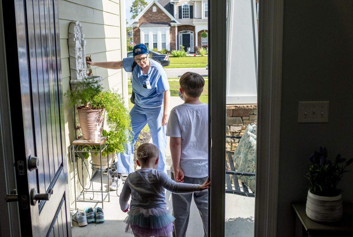 Jacob (7) and Ella Hahn (2) greet their mother Kelly Hahn at the door as she returns from her nursing job where she works screening patients for the coronavirus. When Hahn arrives home, she avoids touching the children until she can get a shower in hopes of keeping her family safe from infection. May 4, 2020