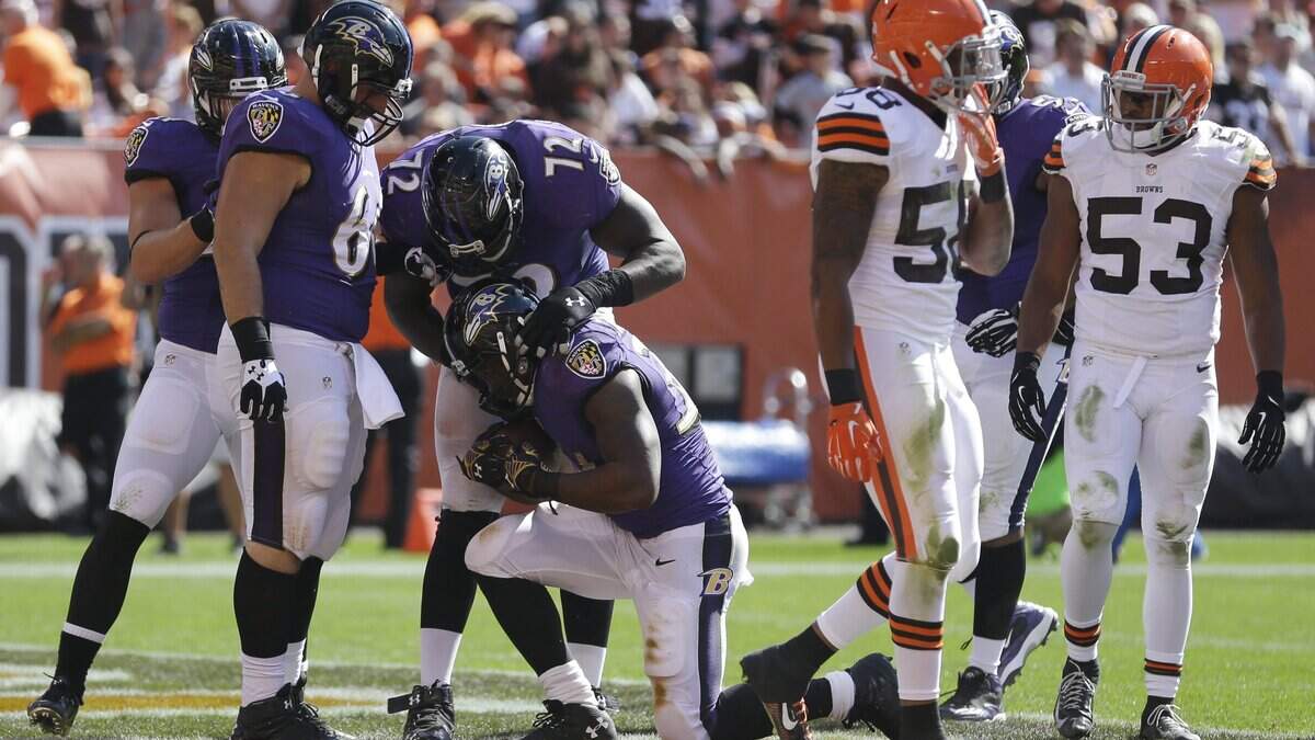 Former Coastal Carolina running back Lorenzo Taliaferro, kneeling, is congratulated by his Baltimore Ravens teammates after a touchdown run against the Cleveland Browns in 2014.