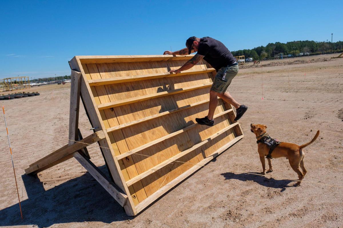 Ryan Small, owner of Beast Ninja Gym, along with his dog “Gunner” demonstrate some of the 30 obstacles he’s built for the Myrtle Beast All Terrain Race planned for May 21, 2022. The three-mile course with obstacles and physical challenges is being built on the site of the former Hard Rock Park off George Bishop Parkway. March 14, 2022.