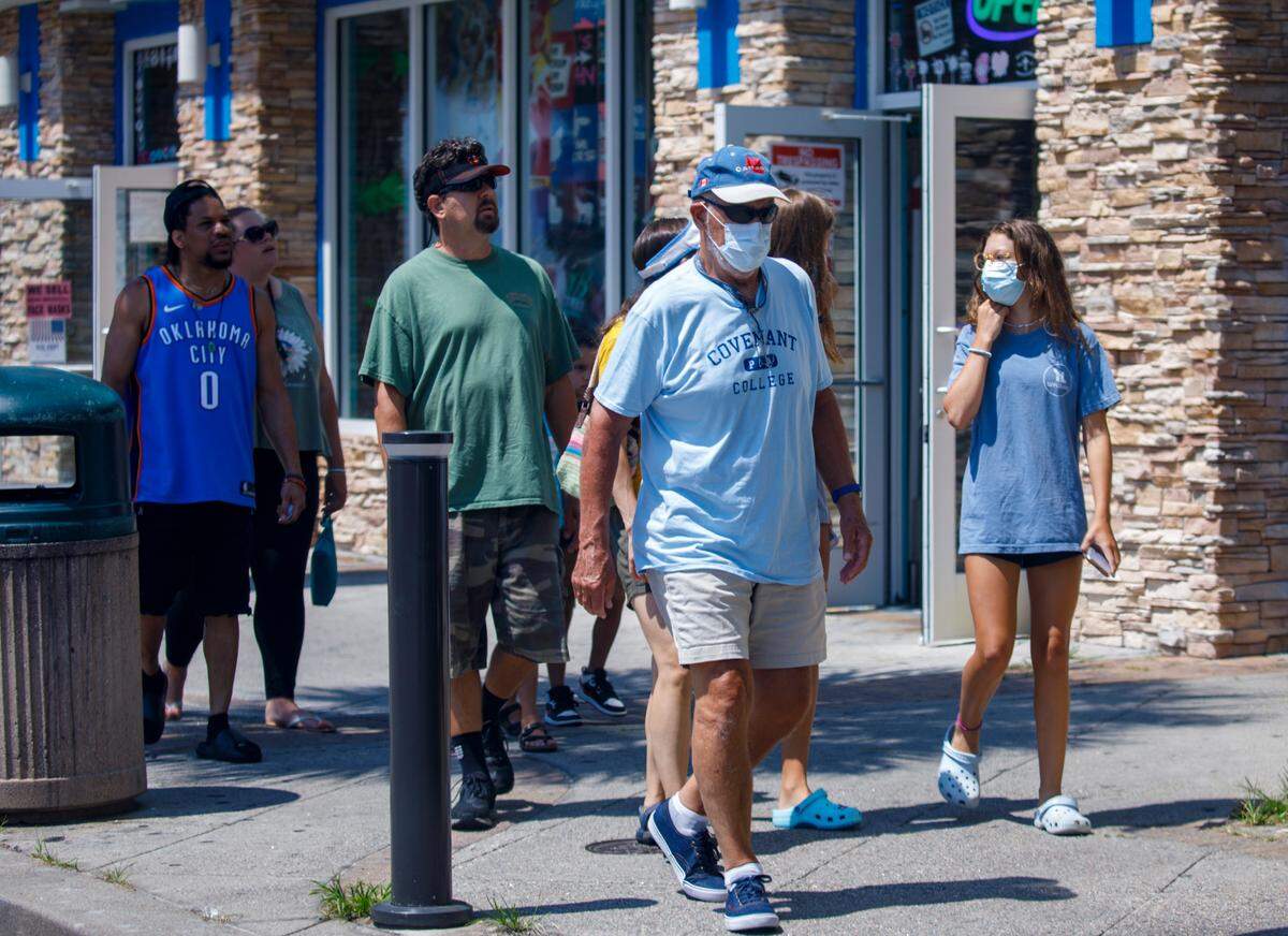 Visitors wear masks while walking on Ocean Boulevard in the Myrtle Beach as COVID-19 spikes again. Aug. 11, 2021.