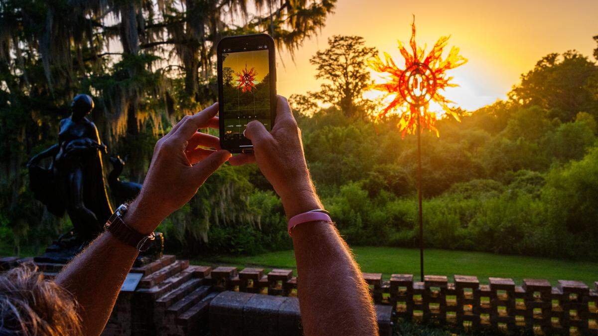 Visitors stroll through glowing art installations at the Summer Light: Art by Night exhibit at Brookgreen Gardens in Murrells Inlet, S.C. A new feature for 2025, Gardens of Glass: The Art of Craig Mitchell Smith, showcases thirty glowing glass sculptures throughout the gardens. The gardens have become a beloved spot to take in the scenery and snap photos that visitors can use to bring their vacation memories home. TSN July 16, 2025 File. 