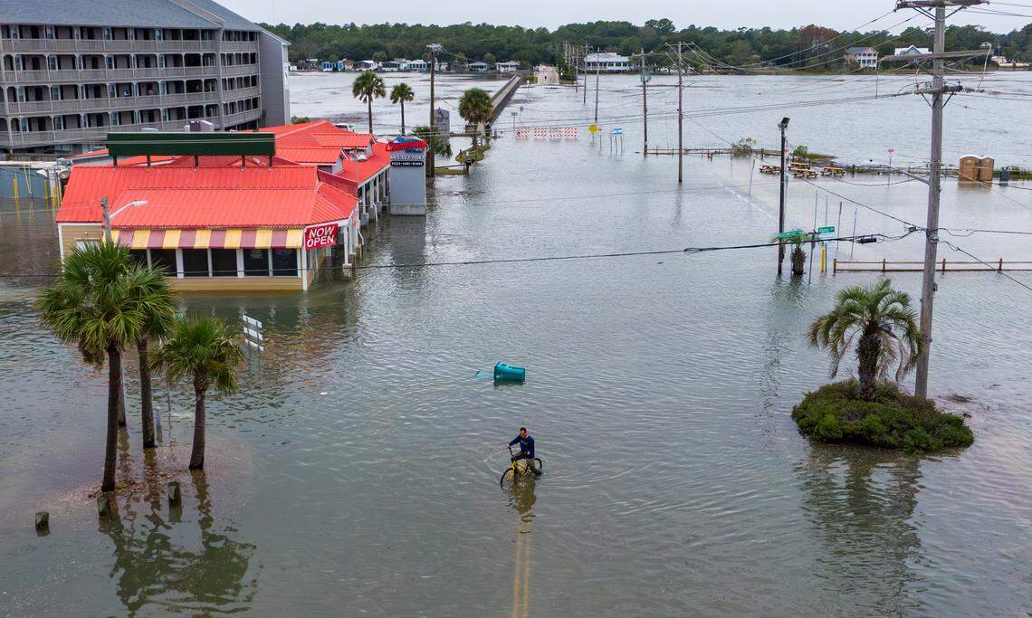A bicyclists pedals through flood waters on Atlantic Avenue. King tides flood the streets of the Garden City community South of Myrtle Beach, SC. The beach town’s low lying streets and businesses flood a few times a year due to the celestial events. Drivers are warned away from driving through flood waters as business owners work to protect their properties. Oct.11, 2025.