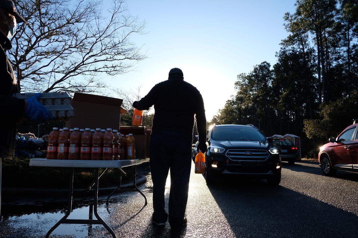 A volunteer with Faith Outreach Ministries awaits cars at a drive-through food distribution event that has tripled its participants due to the pandemic. January 16, 2021.