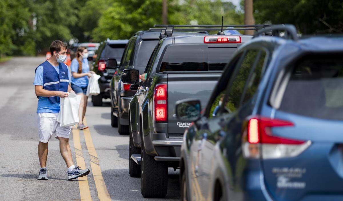 Tidelands Health employees Brian Kirschler and Alyssa Rice hand out registration forms and information packets Saturday morning as Tidelands Health and DHEC conduct a drive-thru COVID-19 testing facility at Pelicans Stadium in Myrtle Beach. Hundreds lined up for the first day of the clinic.