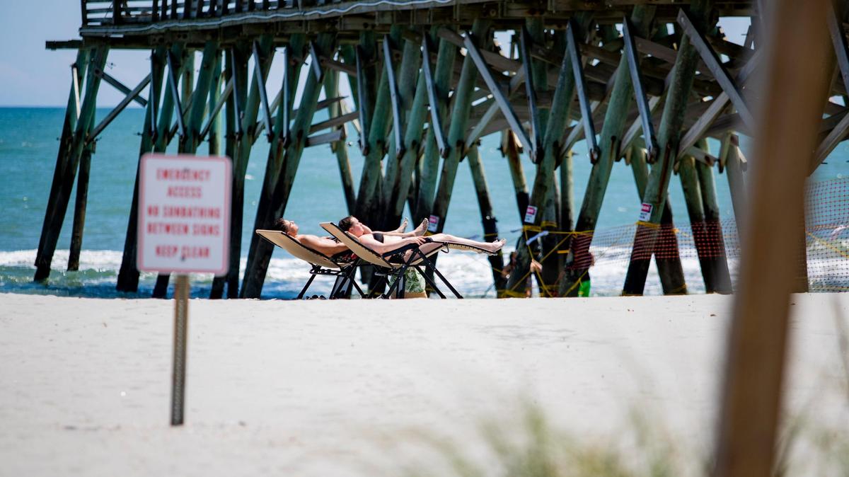 People lay out on the beach near the Surfside Pier in Surfside Beach, S.C.