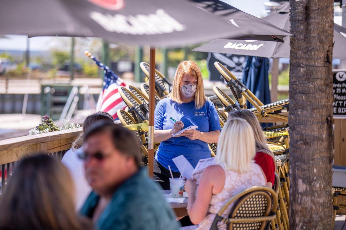 Jennifer Inman, wearing a mask, serves a table of diners at Dead Dog Saloon in Murrells Inlet, S.C. Rules for outdoor dining in South Carolina amid the coronavirus were relaxed on Monday. May 4, 2020