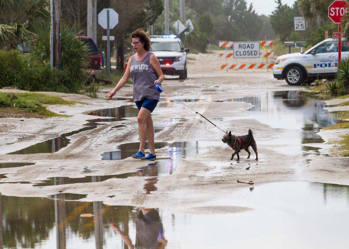 Mary Ann Waymire of Cincinnati, OH picks her way through flooded sand covered streets with her dog “Princess” on the South End of Pawley’s Island. Sept. 12, 2017