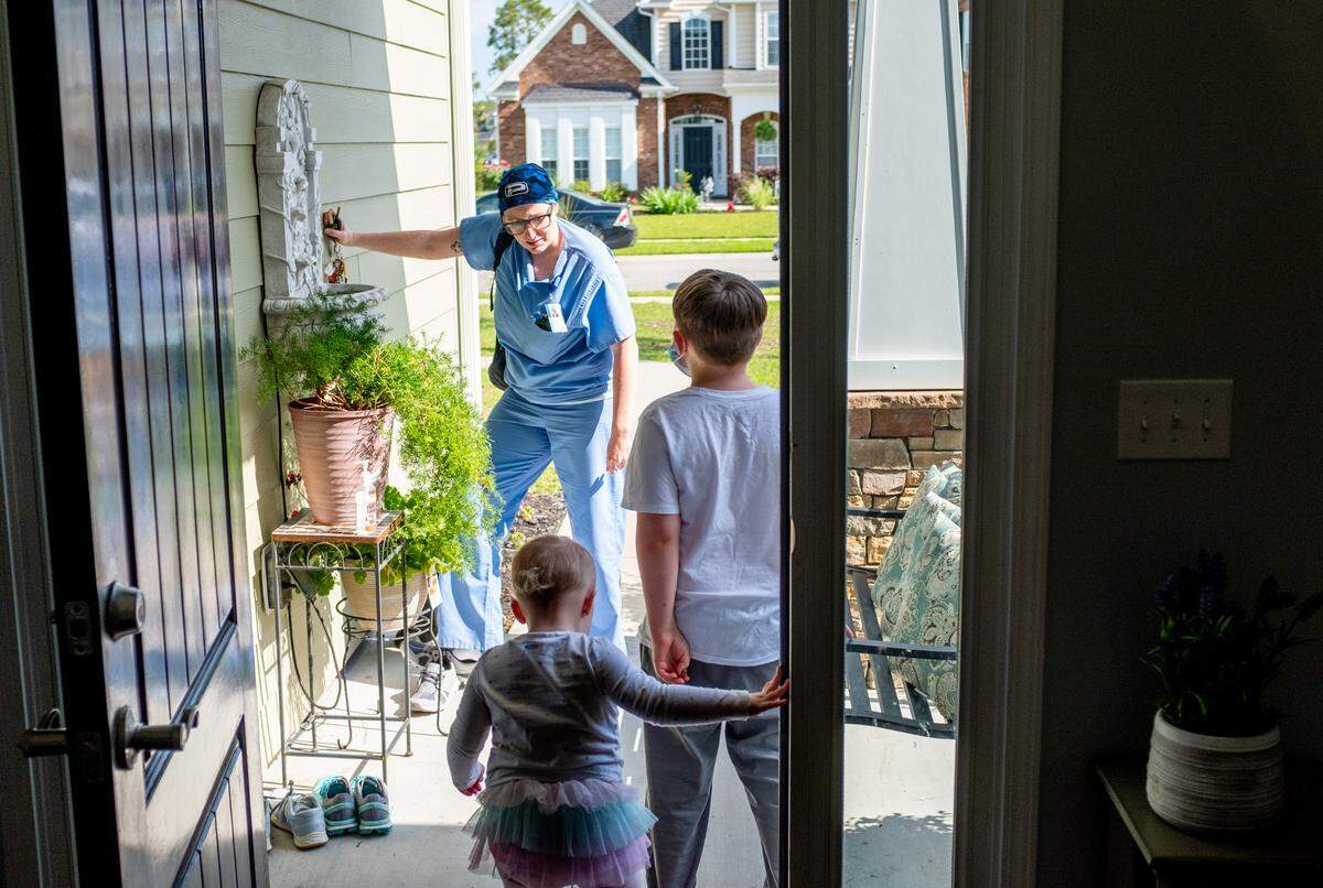 Jacob (7) and Ella Hahn (2) greet their mother Kelly Hahn at the door as she returns from her nursing job where she works screening patients for the coronavirus. When Hahn arrives home, she avoids touching the children until she can get a shower in hopes of keeping her family safe from infection. May 4, 2020