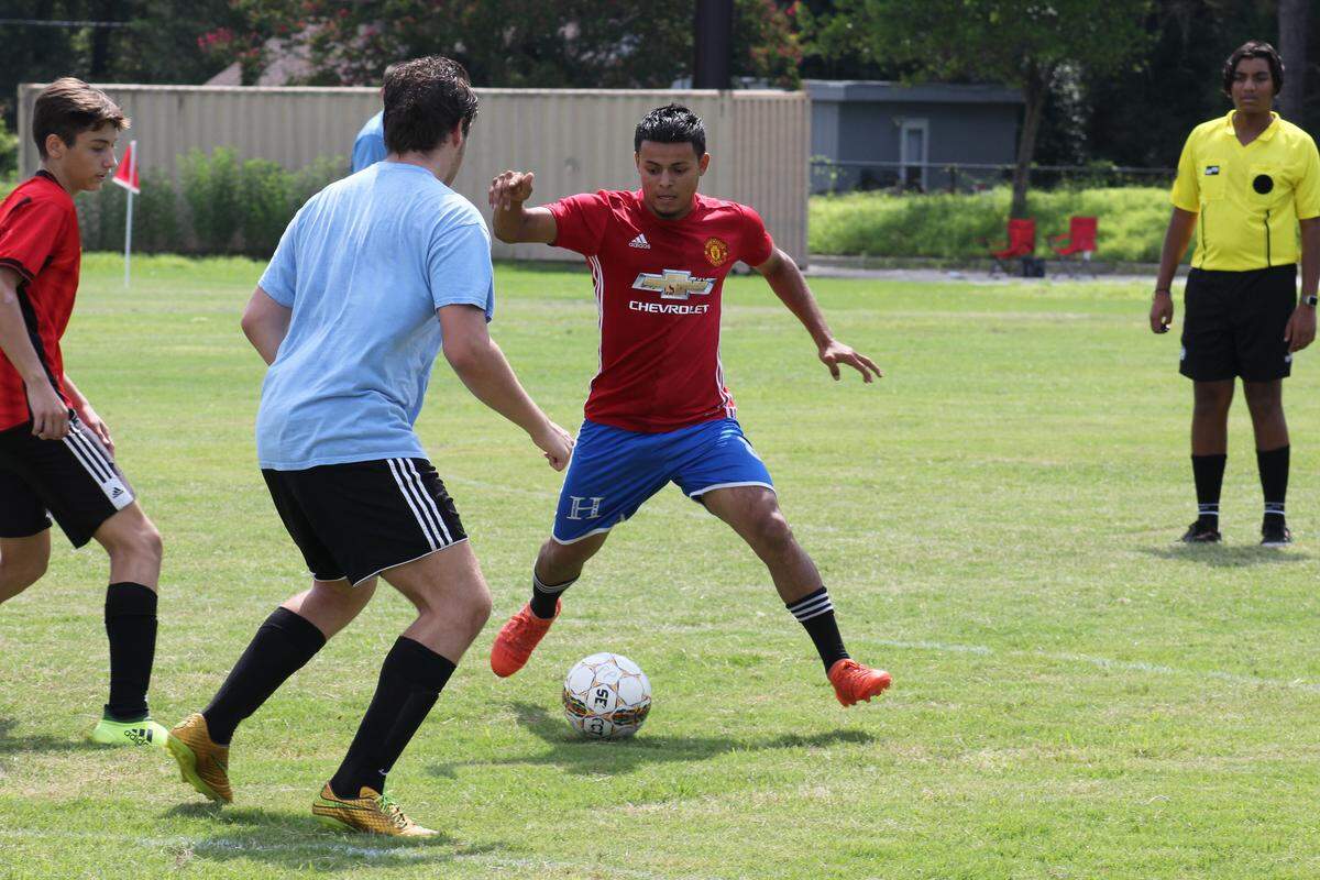 A member of the Legends soccer team (in red) kicks the ball past a Chicago FC player (in blue) during a charity soccer tournament raising money to send soccer equipment to kids in Costa Rica and Nigeria.