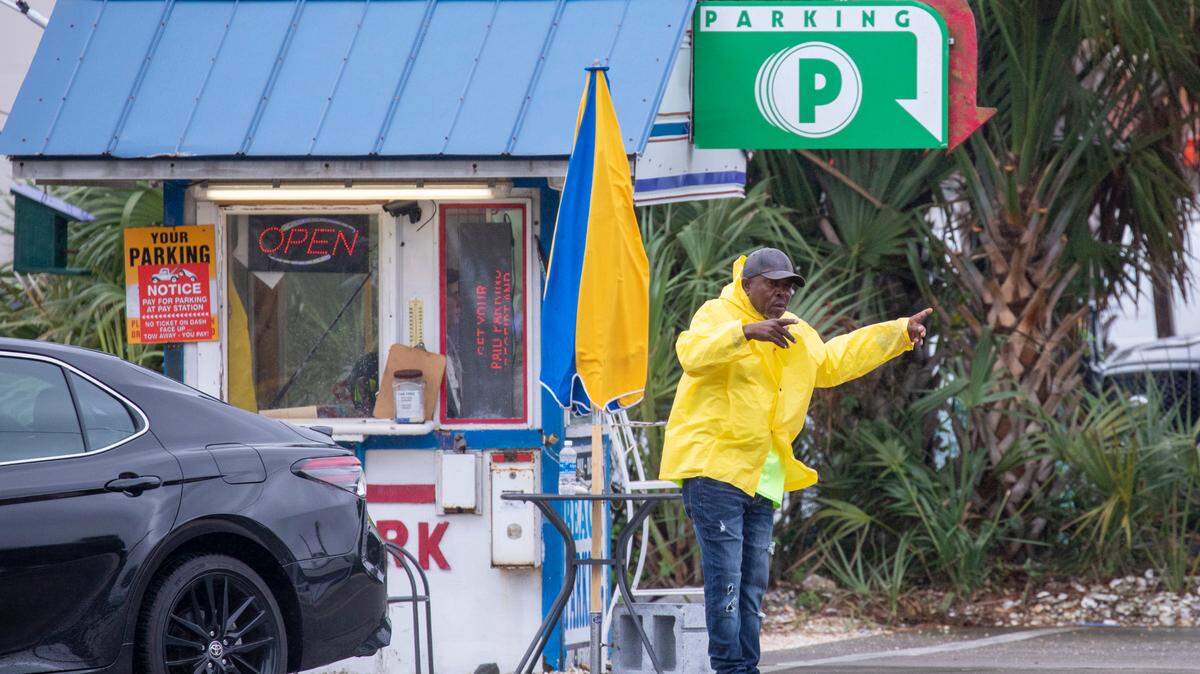 A parking lot attendant attempts to wave cars into his lot but there were many vacant parking spaces in downtown Myrtle Beach on May 27, 2023.