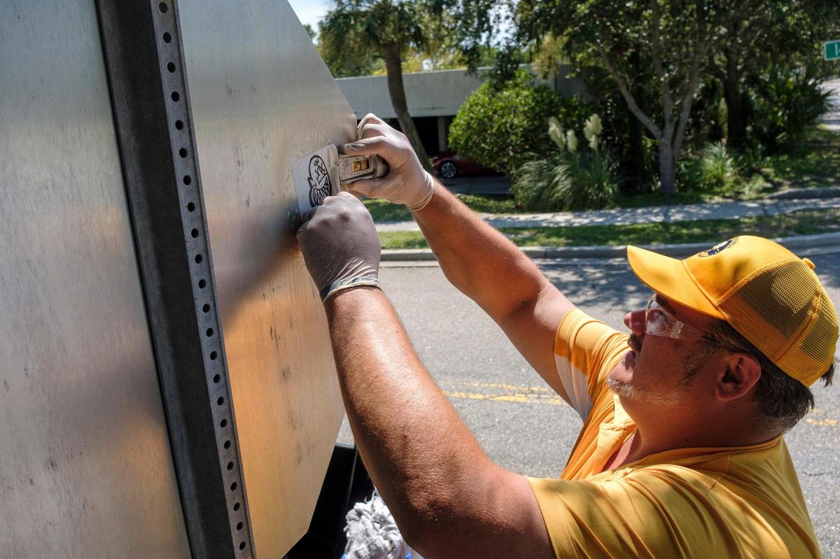 Jeremy Trendle removes stickers placed on a stop sign in downtown Myrtle Beach on Wednesday afternoon. A dozen Gold Cap Ambassadors are now patrolling the streets of Myrtle Beach cleaning up trash, providing hospitality services, and reporting issues to city officials.The pilot program started in August as a way to improve the safety and cleanliness of the tourism district. August 26, 2020.