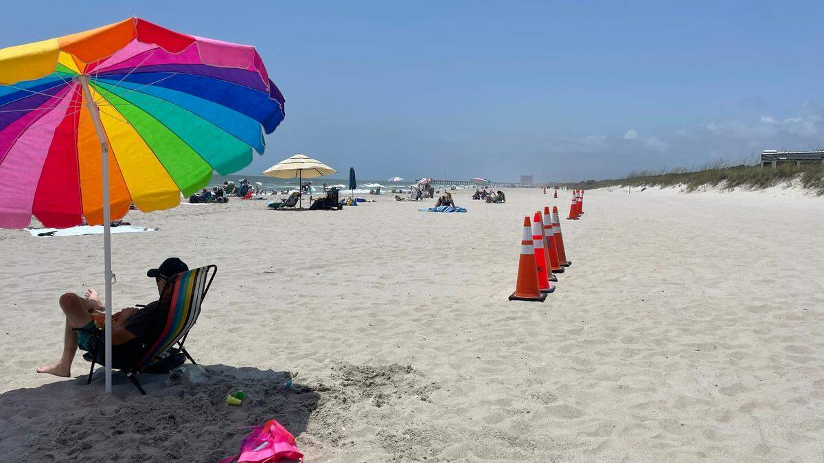 A beachgoer on June 25, 2024, sits near orange cones that have been placed on an Horry County beach near the Nash Street beach access. The cones designate the emergency vehicle access lanes. The area was the site of a deadly beach accident in which a Myrtle Beach woman was run over by an Horry County beach patrol vehicle on April 27, 2024.