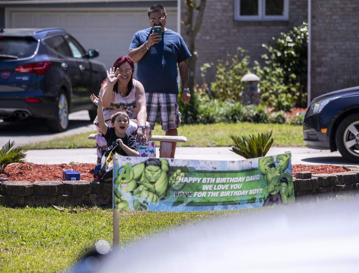 David Koullias waves to a parade of cars on his eighth birthday from his front yard. The coronavirus pandemic has required their father, Nick, a restaurant worker, and mother Melissa, a baker, to become school teachers while they self quarantine at home. May 11, 2020