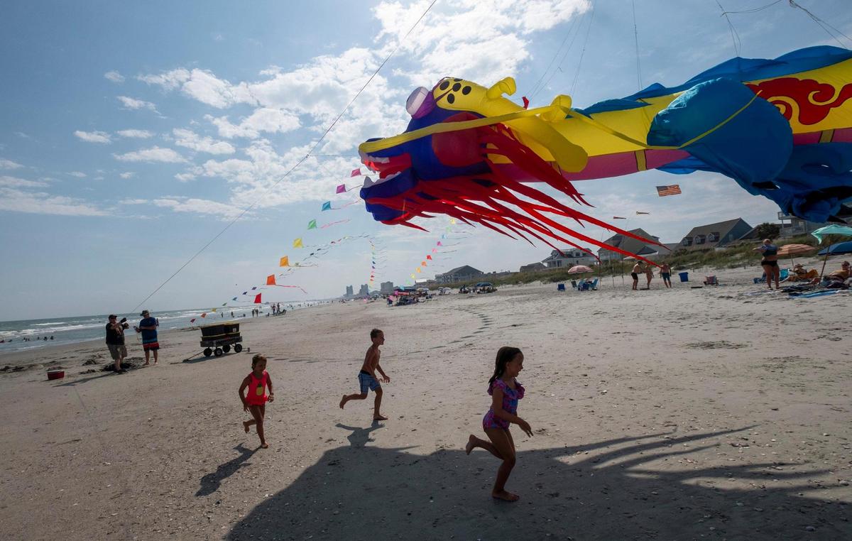 Dale Dove, of Rock Hill, South Carolina, flies his giant Chinese Dragon kite in Cherry Grove section of North Myrtle Beach, S.C. as kids play below. Dove, who grew up in the area, has more than 80 kites and frequently flies them when he comes to visit his mother in North Myrtle Beach, S.C. July 20, 2023.