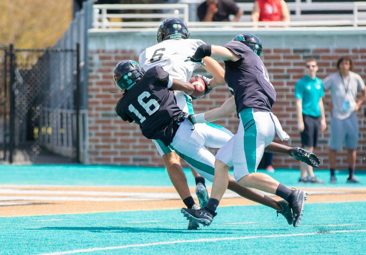 Freshman Kameron Burton and freshman Jordan Morris try to take down receiver Jaivon Heiligh as he completes a 65-yard touchdown reception during Coastal Carolina’s spring game Saturday at Brooks Stadium.