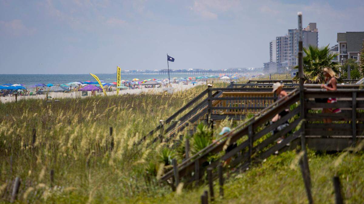 People sit along the beach in Surfside Beach Saturday afternoon.