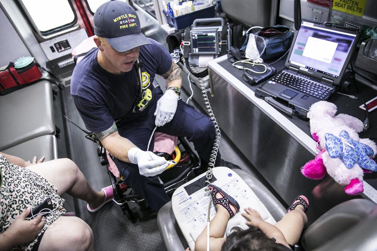 Myrtle Beach Fire Rescue Engineer/Paramedic Ross Porter treats a child patient in the in the back of his ambulance providing the child with stuffed animals to sooth her fears. Porter has served with the MBFR for 10 years. Aug. 7, 2018.