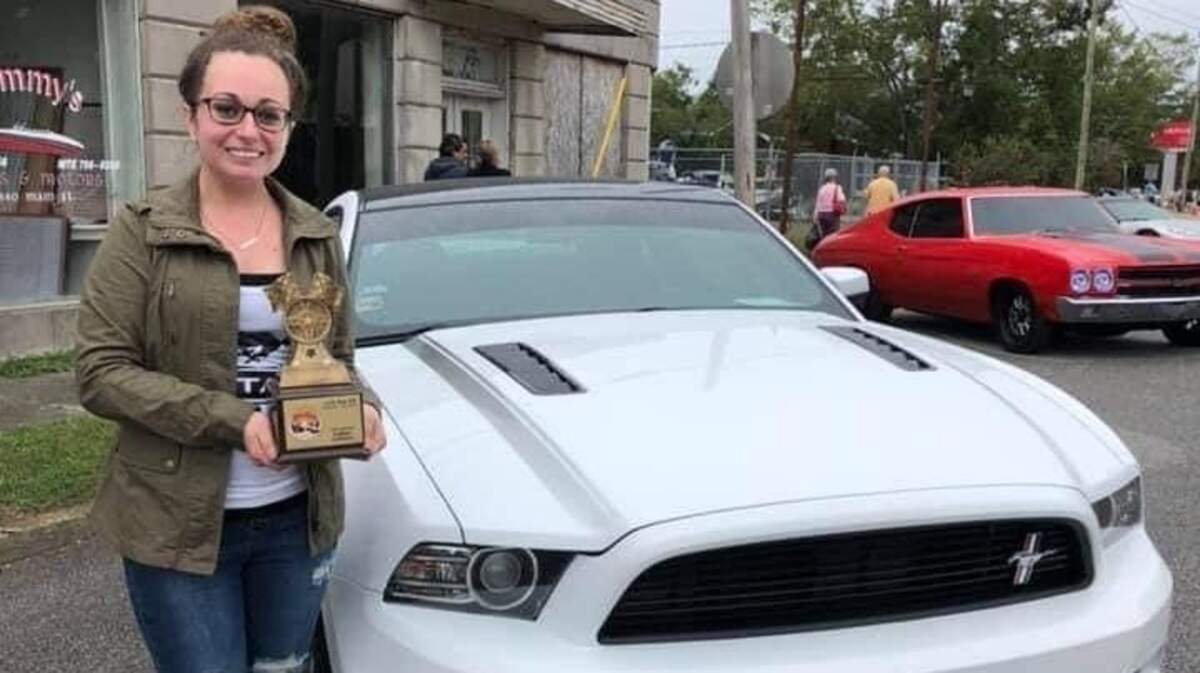 Jessica Hughes holds a trophy next to her prized Ford Mustang.