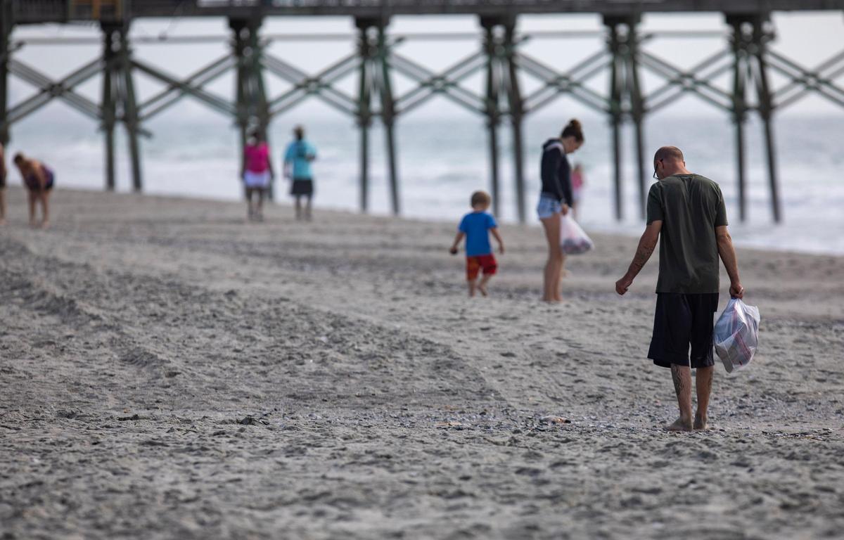 Stephen and Heather Szudy of Chicago, Ill. collect seashells in plastic bags on the beach in Myrtle Beach Friday.