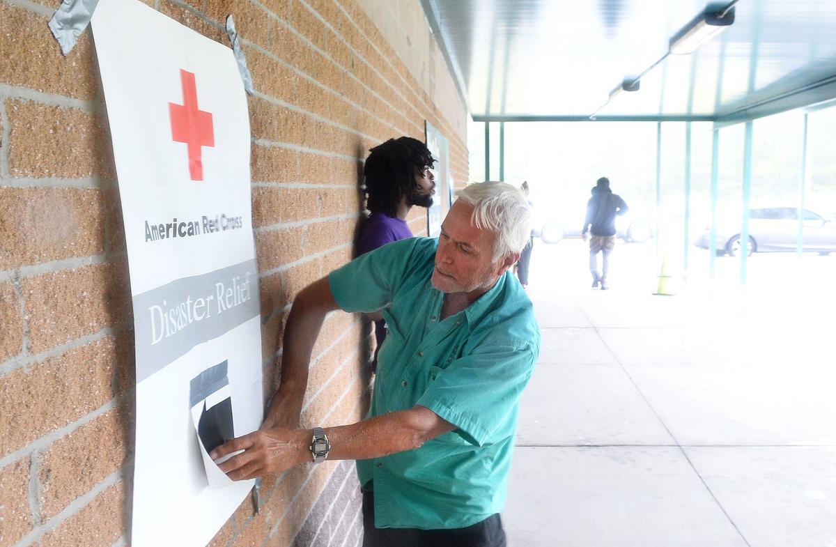 Rick Cruz tries to reattach the Red Cross Disaster Relief Center sign in winds at Palmetto Bays Elementary in Myrtle Beach on Sept. 14, the day Hurricane Florence came ashore at Wilmington, N.C. Cruz and his wife were in the area to sell their vacation home and had to evacuate to a shelter at the school.