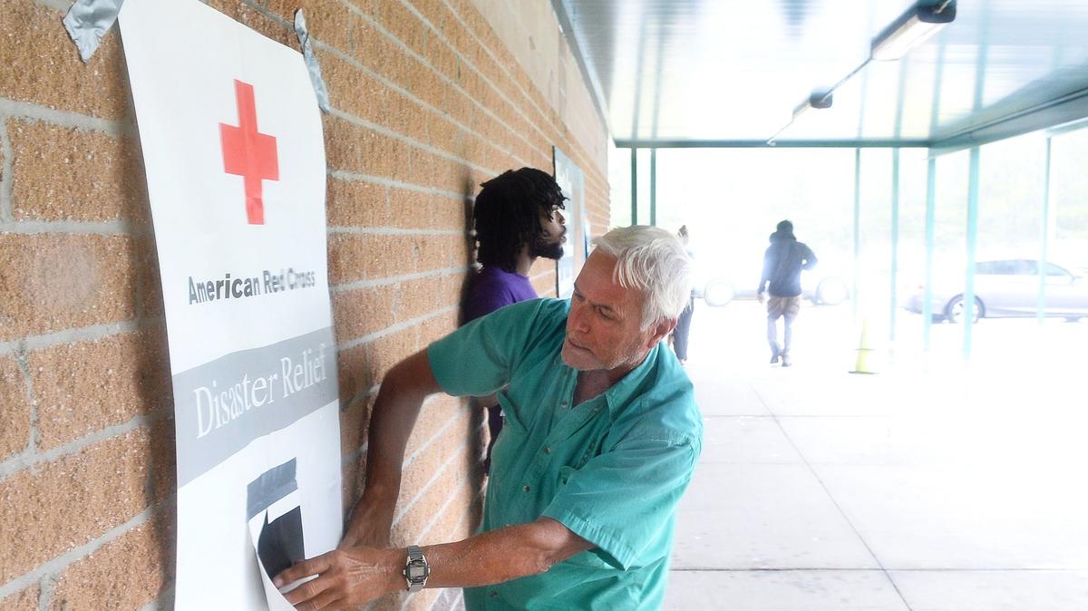 Rick Cruz tries to reattach the Red Cross Disaster Relief Center sign in winds at Palmetto Bays Elementary in Myrtle Beach on Sept. 14, the day Hurricane Florence came ashore at Wilmington, N.C. Cruz and his wife were in the area to sell their vacation home and had to evacuate to a shelter at the school.