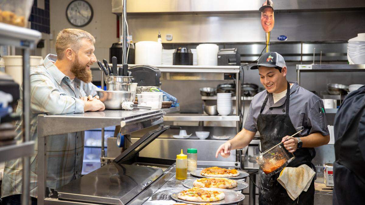 “Chef Swap at the Beach” host Mason Zeglen speaks to contestant Gabe Hernandez as he cooks in the kitchen of Nonna’s Taste of Italy.