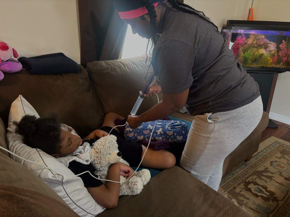 Shanekia Grissett flushes her daughter’s G-tube after a meal. Grissett, who has a disabled daughter, is facing eviction from her home, which she said her landlord has severely neglected.