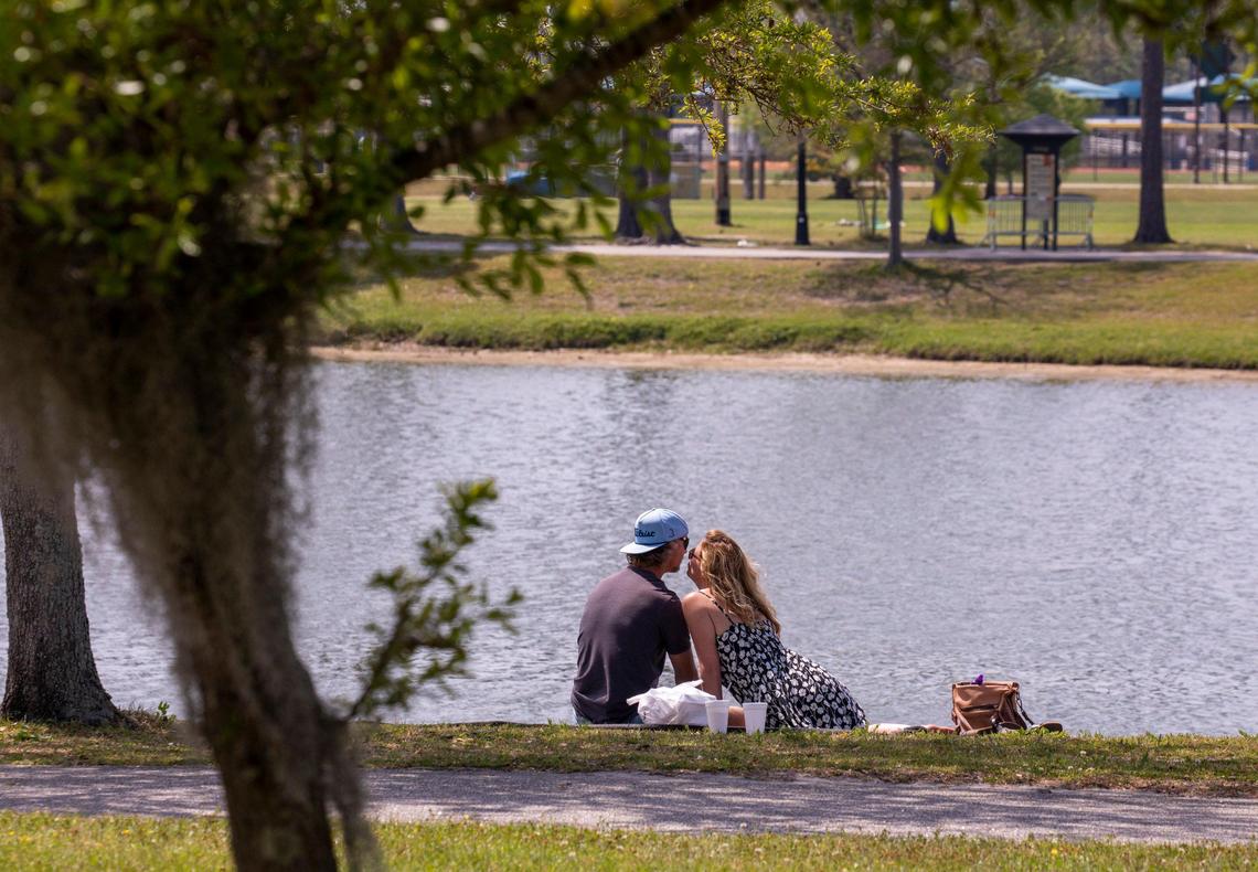 A couple sits on the grass for a picnic lunch beside the Market Common Grand Lake. April 7, 2020