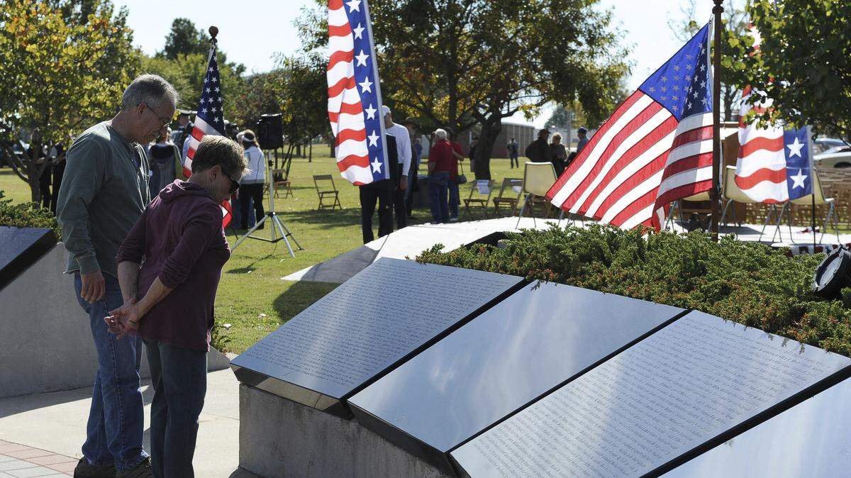 This photo taken Nov. 11, 2016, shows a couple looking at the names on the Cleveland County Veteran’s Memorial during the Veterans Day and Memorial Ceremony, in Reavs Park in Norman, Okla.