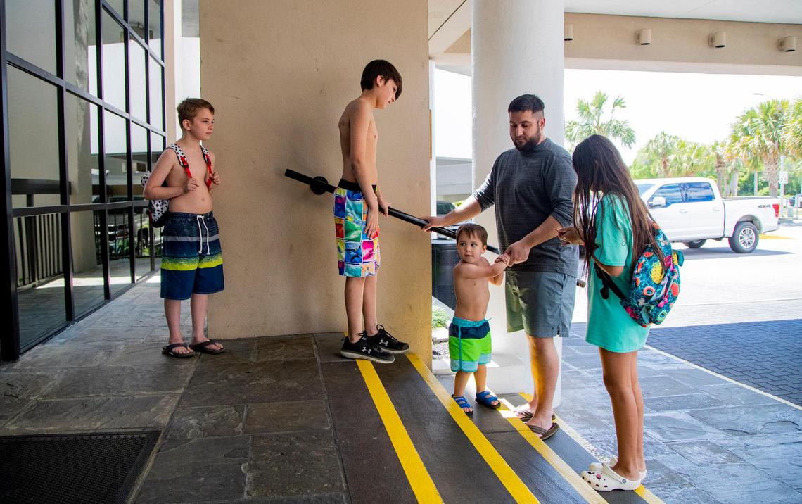The Ramos family of Gaffney, S.C. waits outside the lobby of Captain’s Quarters along Ocean Boulevard Friday afternoon as Myrtle Beach hotels and short-term lodging rental businesses prepared to reopen after county and municipal governments lifted restrictions on reservations forced by the coronavirus outbreak.