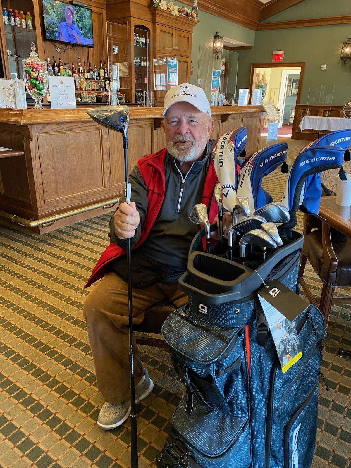 Jimmy Dean sits in the Pine Lakes Country Club pro shop after receiving a golf bag and set of clubs from other club members to commemorate reaching his goal of playing 367 rounds in 2020.