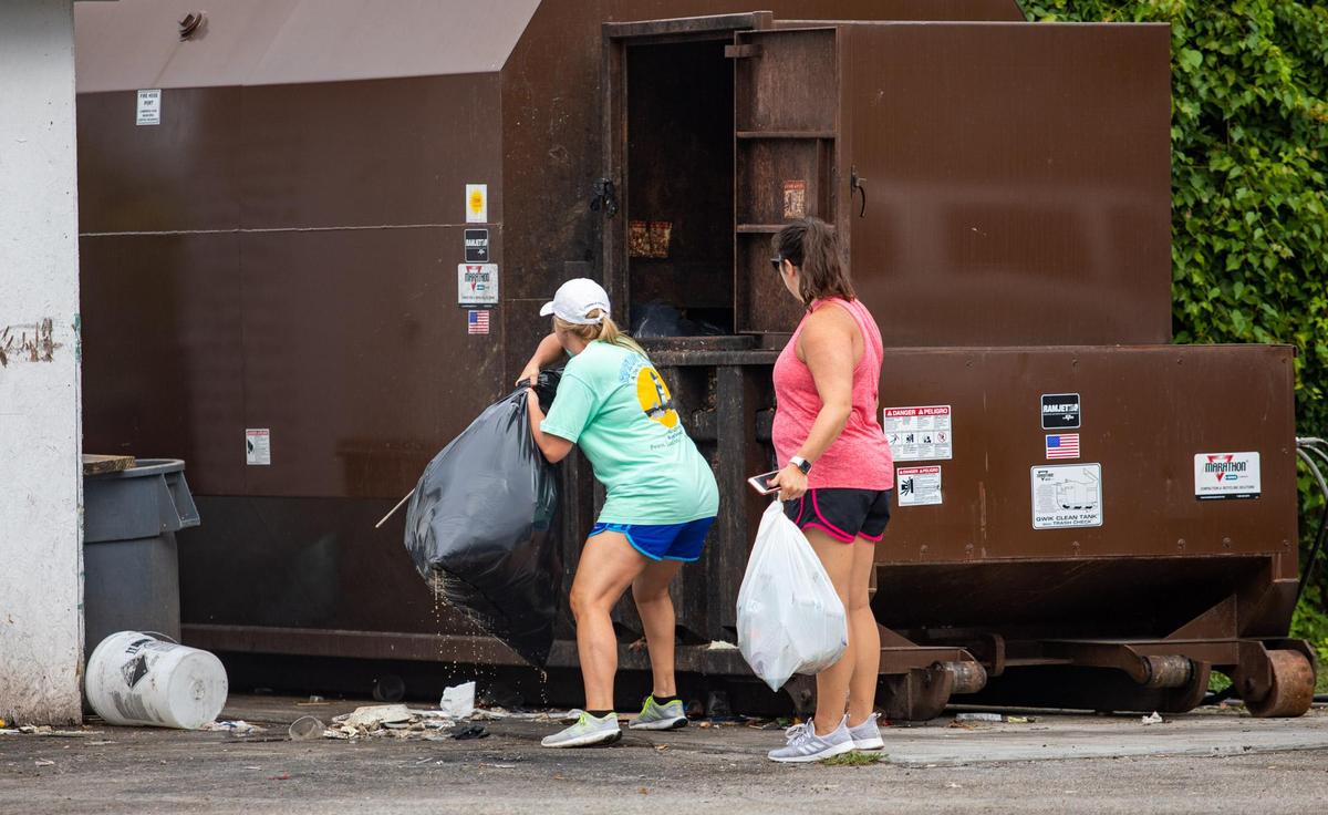 Katie Ford (L) and Amanda Millen of Murrells Inlet throw bags of trash away Friday morning from litter left over from Thursday evening’s July 4 festival at the Murrells Inlet MarshWalk.