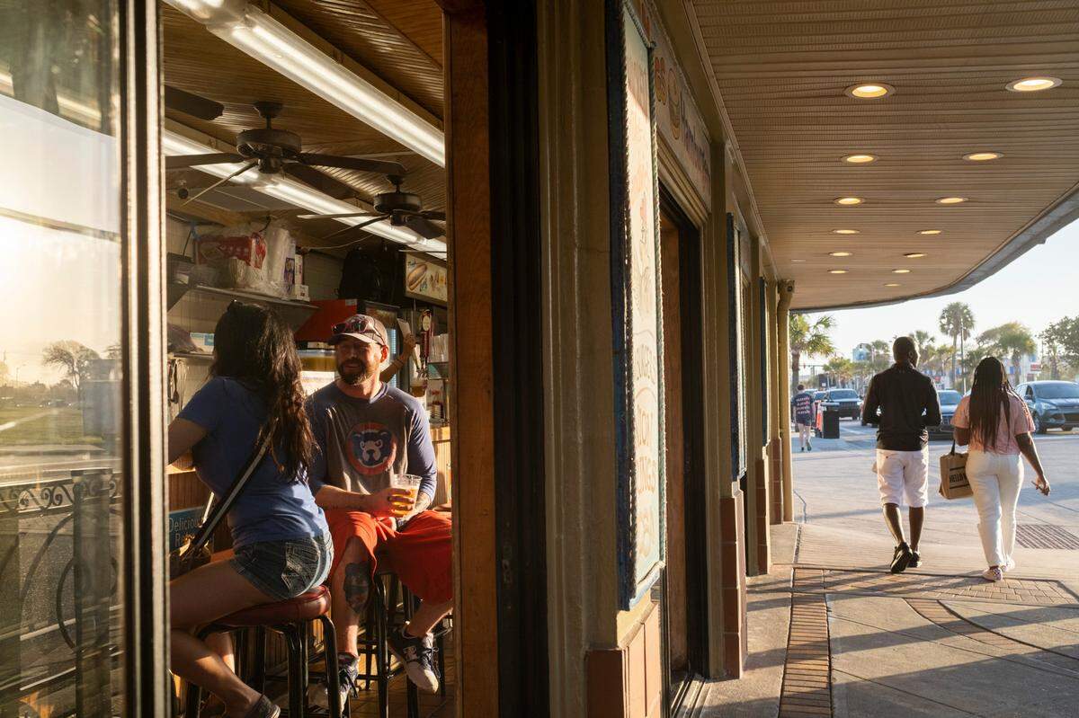 Customers sit at the bar at Peaches Corner and watch visitors pass on Ocean Boulevard in Myrtle Beach on Friday. Grand strand residents and visitors head for the beach on the first sunny weekend of Spring. March 24, 2023.
