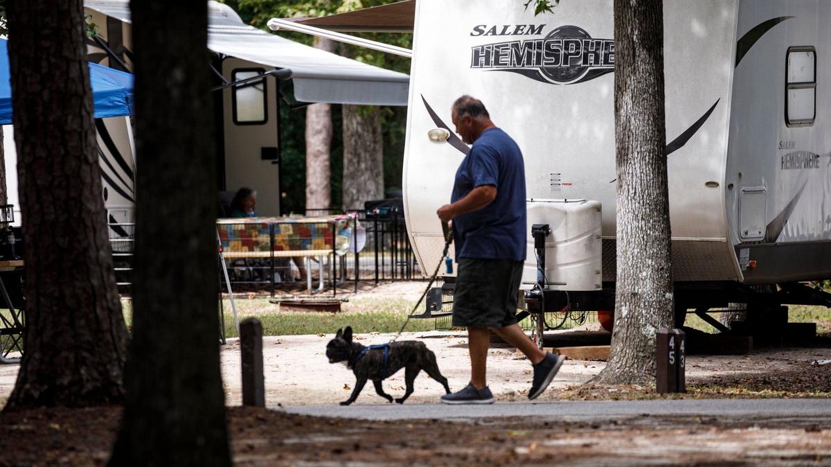 A camper walks his dog through the campground area at Myrtle Beach State Park. Sept. 4, 2024.