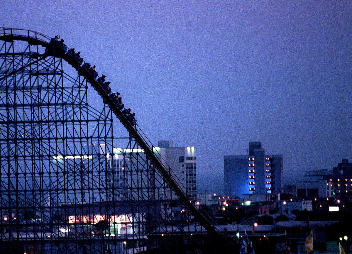 Myrtle Beach’s skyline of hotels and T-shirt shops glow on a hazy evening while a car from the Hurricane roller coaster loaded with people begins the downward slope at Myrtle Beach Pavilion Amusement Park on Tuesday, May 15, 2001.