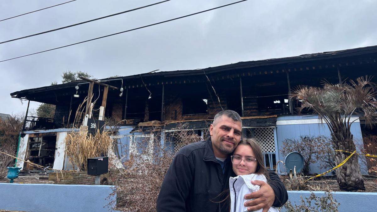 Michael and Adrienne Reinard pose in front of Atlantic Sands apartment complex. The Reinards used to live at the former hotel before the building caught fire on Christmas Day 2024.