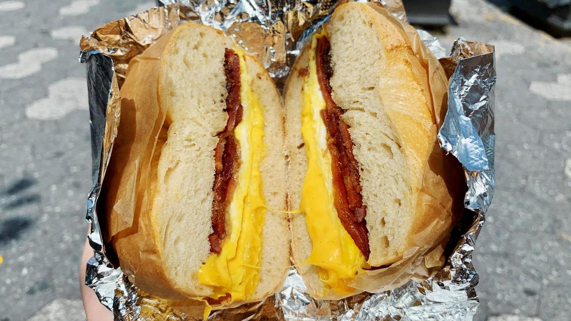 A delicious bacon, egg, and cheese sandwich—or BEC—made on a fluffy plain bagel from a local New York City bagel shop in Brooklyn, New York.