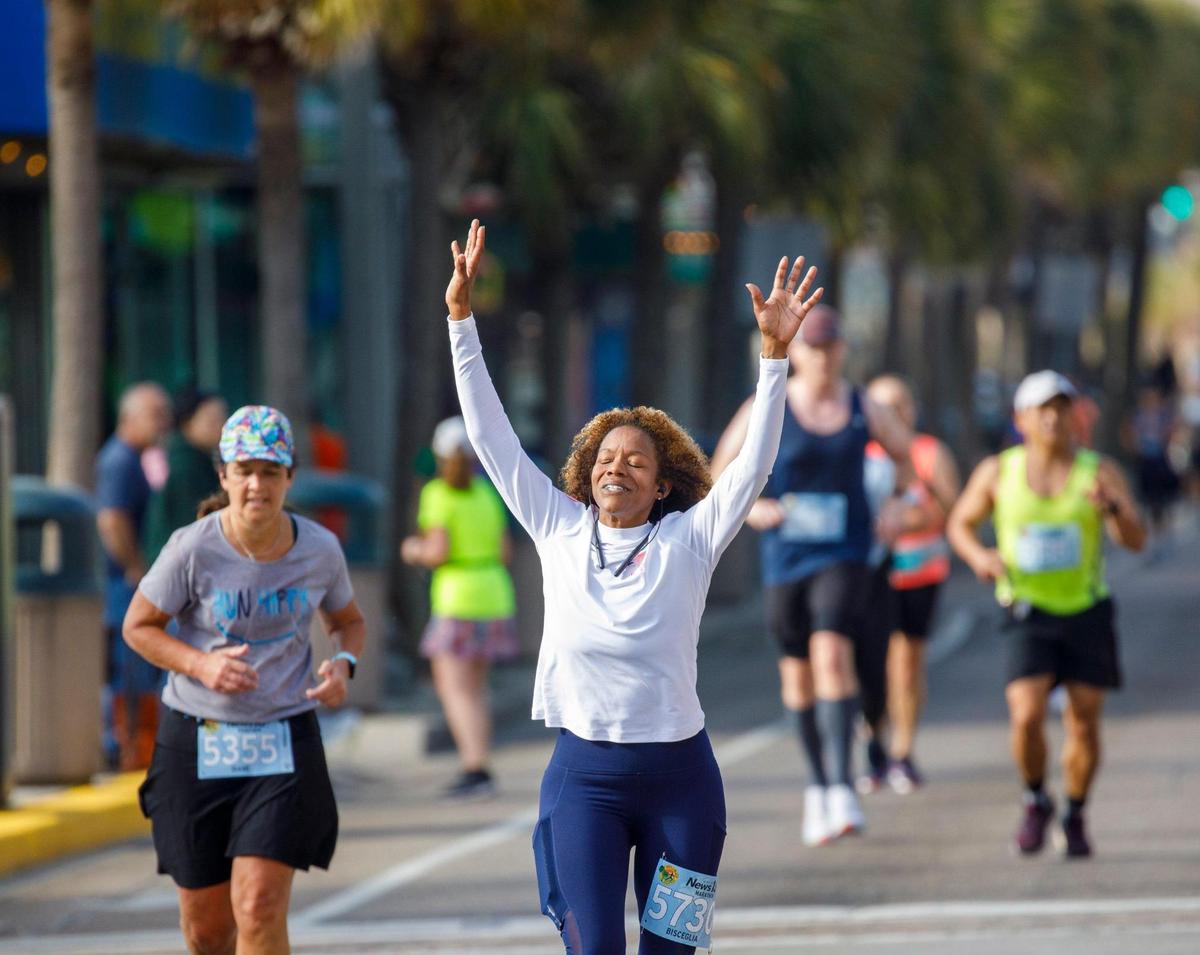 Bisceglia Gaston of Fayetteville, N.C. raises her hands and face to the sun as she and other runners are cheered by fans on Ocean Boulevard during the 25th Myrtle Beach Marathon that was held Saturday. Approximately 4.500 runners participated in the full marathon, half marathon and 5K races. . March 05, 2022.